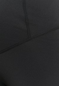 Leggings de sport noirs en tissu lisse et extensible ; dotés de coutures plates et d'un design ajusté pour le confort et la flexibilité.