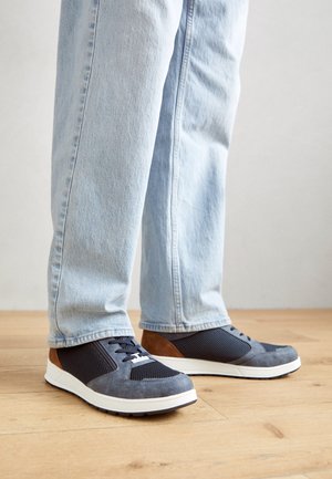 Pantofi sport pentru bărbați cu un amestec de plasă bleumarin și nubuc, cu accente maronii, talpă albă și șireturi negre. Textură fină, design low-top.