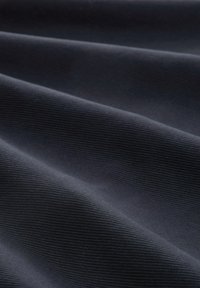 Tissu gris foncé avec une texture fine côtelée horizontale, présenté en pliures douces créant des ombres et des reflets délicats.