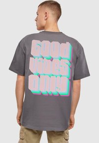 Hallhalline t-särk, millel on suur retro stiilis "Good Vibes Only" tekst roosa ja akvavärviga ning 3D efekt seljal. Lühikesed varrukad, mugav lõige.