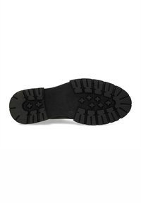 Suela de zapato de goma negra con un patrón de banda de rodadura prominente que presenta surcos y crestas profundas para tracción y estabilidad.