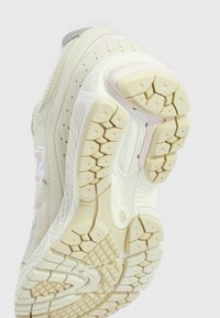 White athletic shoe outsole with textured grooves and patterns; features a pink accent and branding. Surfaces show wear patterns.