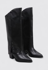 Botas de cuero negro hasta la rodilla con punta afilada y tacón de bloque, que presentan un diseño de solapa y acentos de remaches en el lateral.
