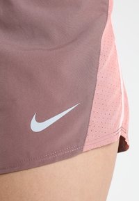 Nike-Sportshorts mit Farbblockdesign; der obere Bereich in Mauve, der untere in Hellrosa, mit weißem Logo und perforierter Textur.
