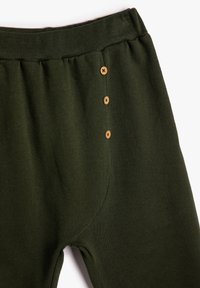 Pantalones de punto verde oscuro con cinturilla elástica acanalada y tres pequeños botones de madera a lo largo de la costura central delantera.