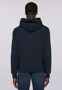 Mörkblå hoodie med justerbar snörning i huvan, ribbade ärmslut och en avslappnad passform, tillverkad av mjukt bomullsmaterial.