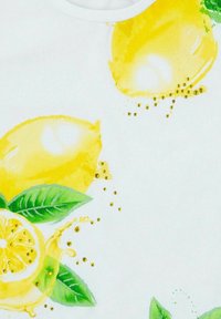 Tela blanca con vibrantes limones amarillos y hojas verdes, con pequeños acentos dorados. El diseño es juguetón y fresco.