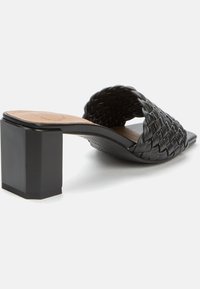 Černé klínové mule s tkanou koženou svrchní částí a čtveratým blokovým podpatkem, s hladkým vnitřkem a texturovaným povrchem.