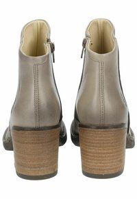Botas de tobillo de cuero marrón con un tacón texturizado color marrón claro, cierre de cremallera en la parte posterior y un acabado suave. Diseño de puntera redondeada.