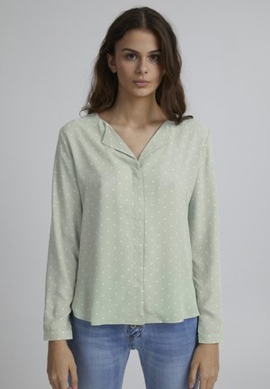 Mint green long-sleeve shirt with white polka dots, soft fabric, and a notch collar, paired with blue jeans.