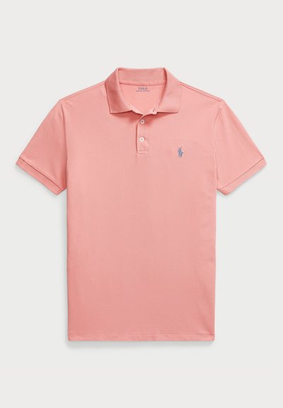 Svetlo roza polo majica z rebrastim ovratnikom, z tri gumbi na zapenjanju in izvezenim modrim logotipom na levi prsni strani. Kratki rokavi in gladka tekstura.