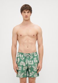 Πράσινα μαγιό με λευκό αφηρημένο σχέδιο φύλλου. Το υλικό είναι ελαφρύ με ελαστική μέση και κλείσιμο με κορδόνι.