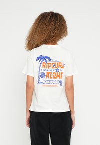 Hvid bomulds T-shirt med korte ærmer med en farverig grafik på ryggen af palmer og teksten "Rip Curl House of Aloha" i orange og blå.