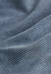 Sinine soonikkangas tekstuurse pinnaga, millel on õrnad varjundimuutused ja pehme viimistlus, langeb õrnades lainetes.