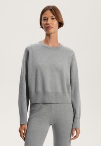 Grauer Pullover aus weichem Material, mit Rundhalsausschnitt, langen Ärmeln und einem lockeren, cropped Schnitt mit gerippten Akzenten am Saum und den Bündchen.
