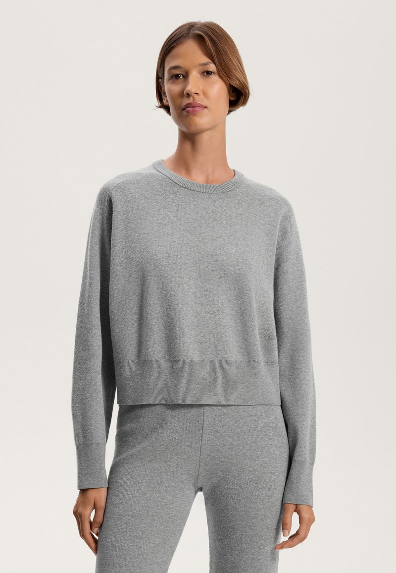 Grauer Pullover aus weichem Material, mit Rundhalsausschnitt, langen Ärmeln und einem lockeren, cropped Schnitt mit gerippten Akzenten am Saum und den Bündchen.