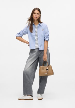 Blue checkered shirt, striped top, gray wide-leg jeans, and white sneakers. Holding a brown handbag with a decorative charm.
