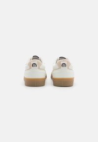 Baskets blanches avec des accents beige clair et une semelle en caoutchouc. Présentent un dessus en cuir lisse, un détail de logo sur le talon et un design bas.