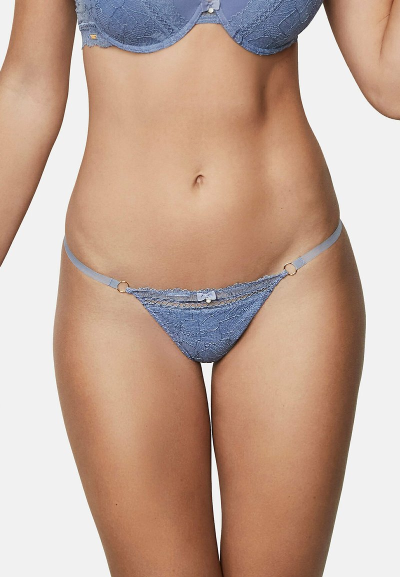 String bleu en dentelle avec motif floral, doté de fines bretelles et d'un petit nœud en accent à l'avant. Le matériau semble doux et texturé.