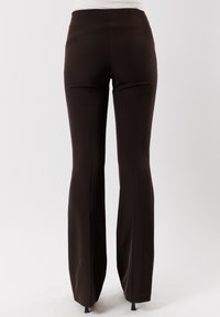 Pantaloni marroni a sigaretta con tessuto morbido e elasticizzato. Vita medio-alta e dettagli eleganti sul retro, adatti per un abbigliamento casual o formale.