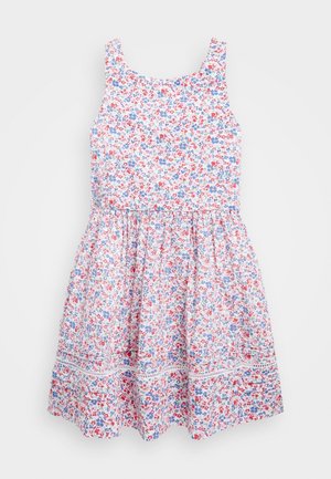 Ærmeløs hvid kjole med små røde og blå blomsterprint og indsamlet nederdel, med vandret blonderibånd nær kanten.