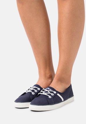 Baskets en toile bleu marine avec lacets et semelle blanche. Présentent un design plat et une bande latérale contrastante. Dessus texturé avec un bout rond.