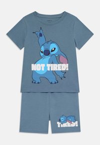 Blauwe katoenen korte pyjama's met een cartoonfiguur met roze accenten. Het shirt toont "NIET MOE!" en de shorts tonen het figuur dat slaapt.