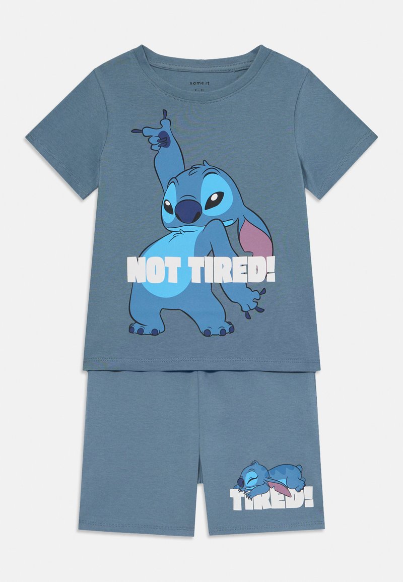 Blauwe katoenen korte pyjama's met een cartoonfiguur met roze accenten. Het shirt toont "NIET MOE!" en de shorts tonen het figuur dat slaapt.