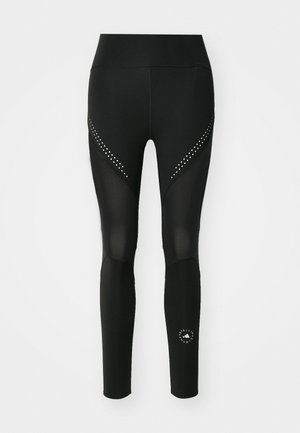 Melna sporta legingi ar acs paneļiem un trīsstūra izgriezumiem, ar sudraba kniedēm gar sāniem un logo uz apakšējās kājas.