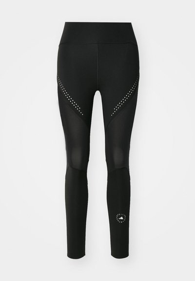 Černé sportovní legíny s síťovinovými panely a trojúhelníkovými výřezy, se stříbrnými cvočky po stranách a logem na spodní části nohavice.