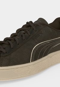 Σκούρο καφέ σουέτ αθλητικό παπούτσι Puma με υφή δέρματος, λευκή πλευρική ρίγα, κορδόνια στο ίδιο χρώμα και κρεμ σόλα από καουτσούκ.
