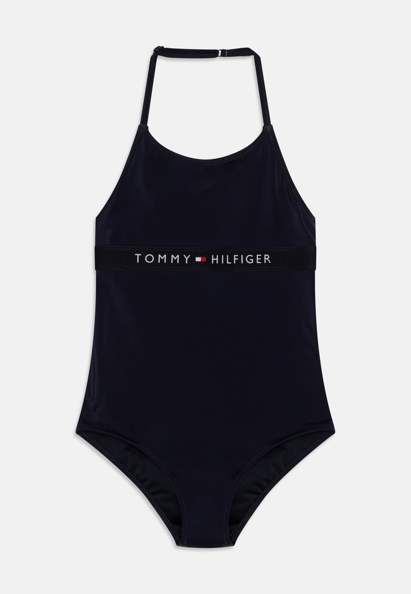 Mørkeblå heldraktbadebukse med tynne stropper og et logo-bånd med "TOMMY HILFIGER" i hvitt og rødt. Glatt, elastisk stoff.