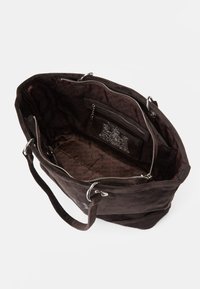 Brun mocka toteväska med en rymlig insida, ficka med dragkedja och silverfärgad utrustning, som har ett mönstrat foder.