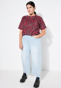 Blommig blus i svart och rött, tillsammans med ljusblå vida jeans. Kraftiga svarta skor och blåmönstrade strumpor fulländar looken.