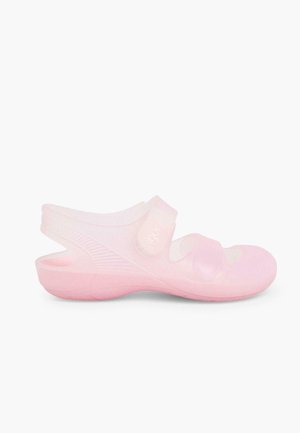 Roze sandaal gemaakt van doorzichtig plastic, met een band en verstelbare klittenbandsluiting. Ronde neus met textuur aan de zijkanten en cushioning.