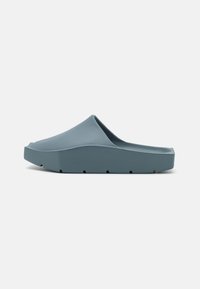 Scarpa blu slip-on, realizzata in gomma testurizzata, con punta arrotondata, suola spessa e piccoli tagli lungo il fondo per la trazione.