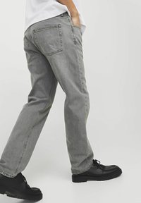 Grijze denims met een rechte pasvorm, vijf zakken en zichtbare stiksels. Gecombineerd met zwarte schoenen met een dikke zool.