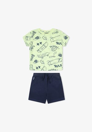 Camisa de manga corta verde claro con dibujos de monopatines y flechas en azul marino, combinada con pantalones cortos de cuerda lisos en azul marino para niños.