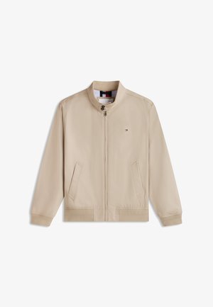 Veste beige zippée avec col montant, deux poches avant, manches longues, et petit logo rectangulaire sur la partie gauche de la poitrine.