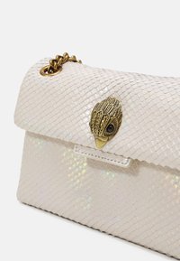 Borsa bianca testurizzata con tracolla a catena, caratterizzata da un motivo a scaglie iridescenti e un clasp a forma di foglia dorata con decorazioni.