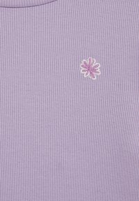 Lila spalvos ribuotas viršus iš minkštos medžiagos, puoštas mažyte rožinės ir baltos spalvų siuvinėta gėlele. Apvali iškirptė ir tekstūruota paviršius.