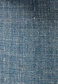 Tejido de denim de color azul medio con una textura entrelazada, que presenta ligeras variaciones en el color y un acabado suave y duradero.