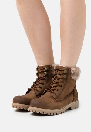 Bottes à lacets marron jusqu'à la cheville, avec doublure en fausse fourrure et suède texturé, équipées d'œillets en métal et d'une semelle en caoutchouc robuste.