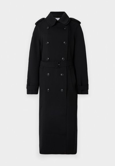 Manteau noir long en tissu doux et texturé. Il présente un système de fermeture à double boutonnage, une taille ceinturée et des épaulettes.