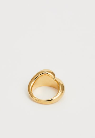 Gold ring with a smooth, curved design featuring a heart shape. The surface is shiny and reflective, with a seamless joining at the top.