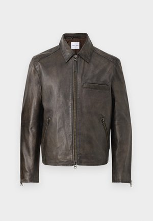 Pruun nahkjakk, millel on lukuga eesmine osa, nööbiga kaelus ja üks rinnatasku. Omab lukuga küljetaskuid ja siledat tekstuuri.