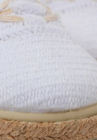Baltos pintos espadrilės su tekstūruotu audiniu, storu jute virvių padu ir apvaliu priekiu. Nėra matomų akcentų ar raštų.