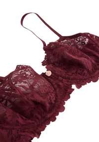 Burgundy lace bra with a scalloped edge, soft cups, adjustable straps, and a small pink rose accent on the center front.