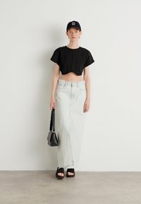 Rövidített fekete póló, világoskék, magas derekú farmer szoknya, fekete platform szandál, fekete sapka, kis fekete kézitáska, sima felület.