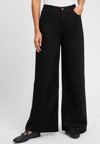 Zwarte wijde broek gemaakt van een lichtgewicht stof, met een sluiting met een knoop aan de voorkant, zijzakken en een gladde textuur.